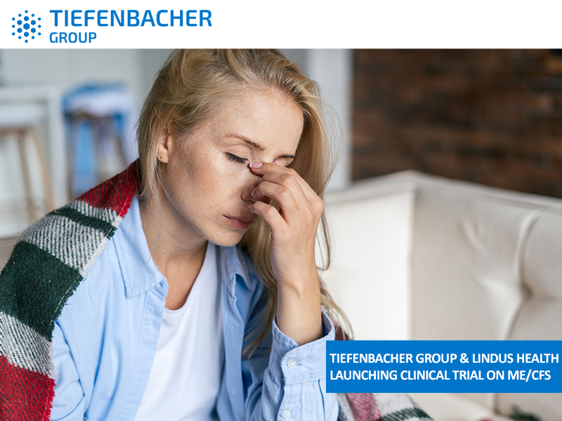 Tiefenbacher Group - A woman sits on a couch with a blanket over her shoulders, eyes closed, pinching the bridge of her nose in discomfort. Text reads: “Tiefenbacher Group & Lindus Health launching clinical trial on ME/CFS and patient-centric drug development.”.