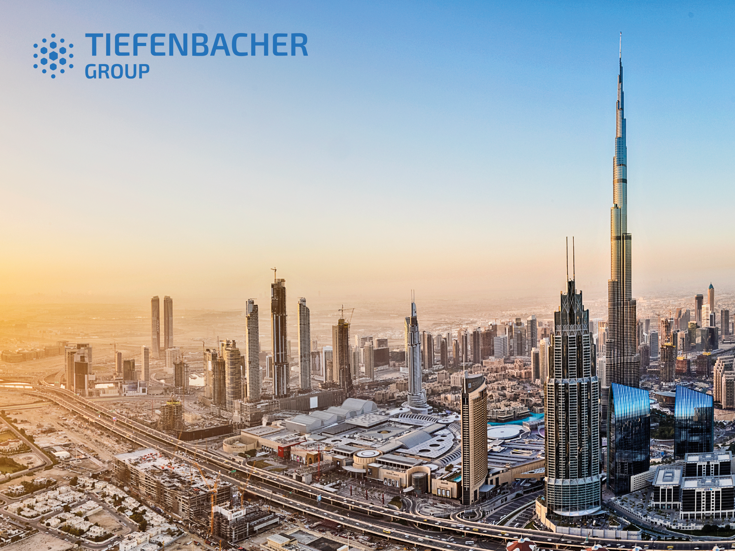 Tiefenbacher Group - A panoramic cityscape of Dubai with the Burj Khalifa towering over other skyscrapers at sunset, highlighting the Tiefenbacher Group—a family-owned pharmaceutical company known for API distribution—in the upper left corner.